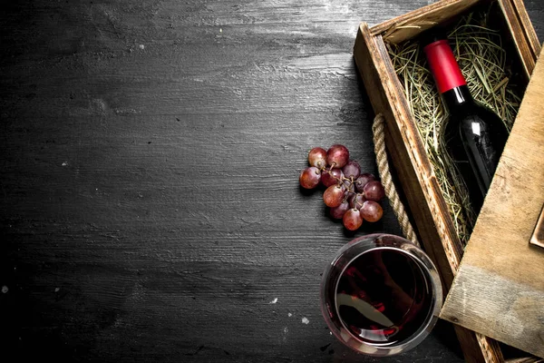 Бутылка красного вина в старой коробке с виноградной ветвью . — стоковое фото