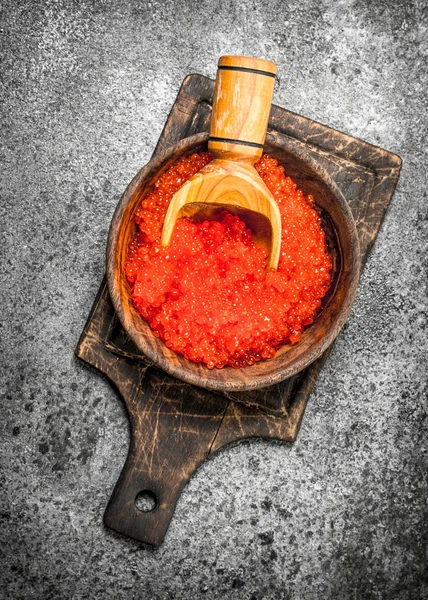 Caviar vermelho em uma tigela de madeira com uma pá . — Fotografia de Stock