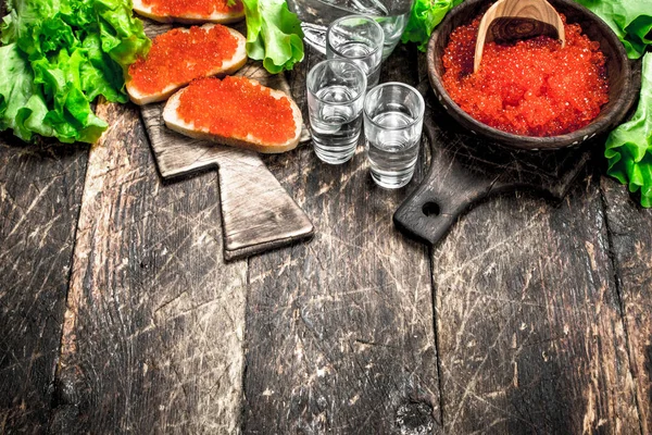 Vodka and sandwiches with red caviar. — Stock Photo, Image