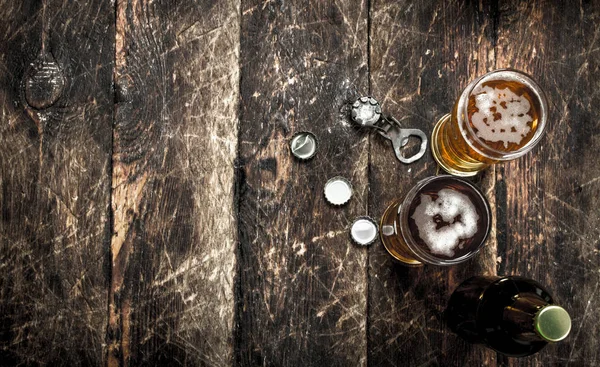 Cerveja fresca em um copo com rolhas e um abridor de garrafas . — Fotografia de Stock