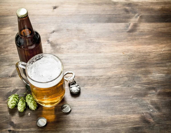 Szklanka piwa z korkami i otwieracz do butelek. — Zdjęcie stockowe
