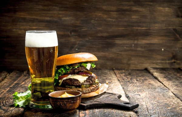 Comida rápida. Una hamburguesa grande con carne y un vaso de cerveza . —  Fotos de Stock