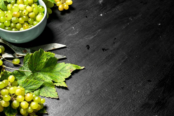 Green grapes in a bowl with leaves. — Stock Photo, Image