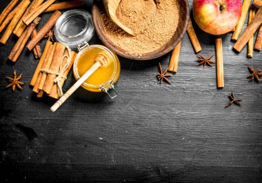 Taze bal tarçın ve bir elma ile. Siyah ahşap bir masa üzerinde.