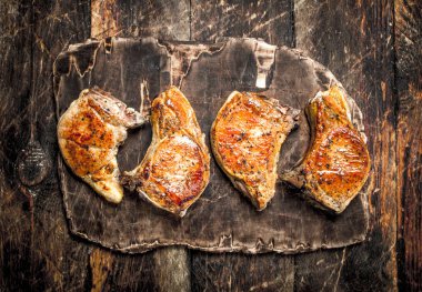 Bir kesme tahtası üzerinde ızgara domuz. Ahşap bir masaya.