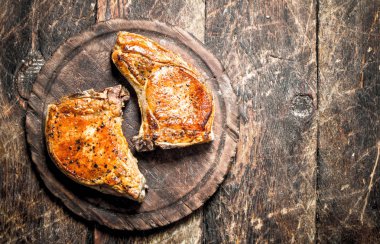 Bir kesme tahtası üzerinde ızgara domuz. Ahşap bir masaya.