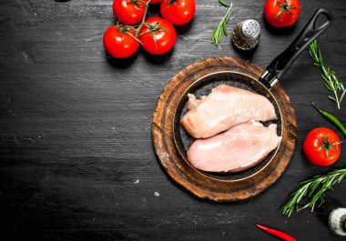 Domates ve otlar ile çiğ tavuk fileto. Siyah kara tahta.