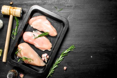 Çiğ tavuk fileto otlar ve baharatlar ile. Siyah kara tahta.