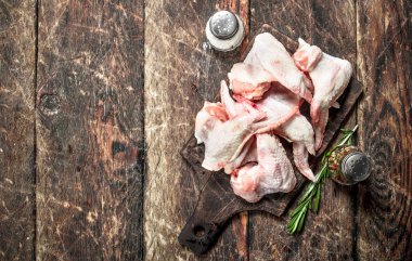 Baharat ve otlar ile çiğ tavuk kanatları. Ahşap bir masaya.