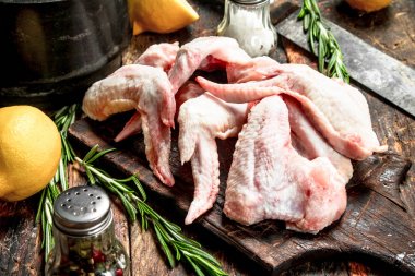 Baharat ve otlar ile çiğ tavuk kanatları. Ahşap bir masaya.