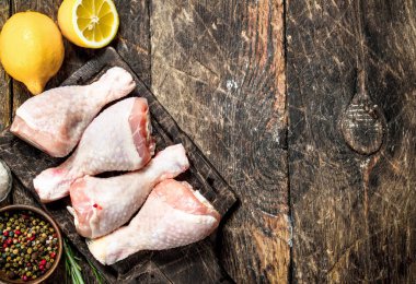 Baharatlar ve limon ile çiğ tavuk budu. Ahşap arka plan üzerinde.