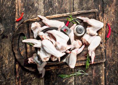 Çiğ tavuk kanadı sarımsak ve bir kase içinde otlar ile. Ahşap arka plan üzerinde.