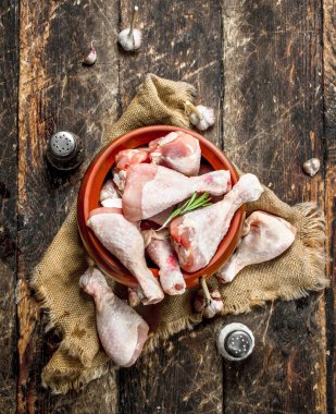 Çiğ tavuk budu sarımsak ve baharat bir kase. Ahşap arka plan üzerinde.