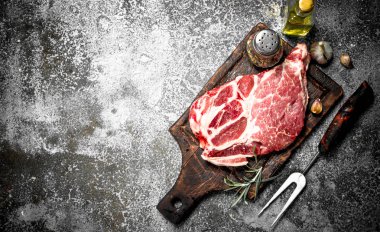 Baharat ve biberiye ile ham sığır eti biftek. Rustik arka plan üzerinde.