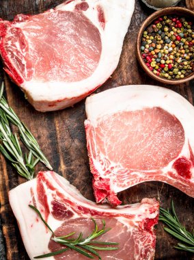 Çiğ domuz biftek otlar ve baharatlar ile. Rustik arka plan üzerinde.