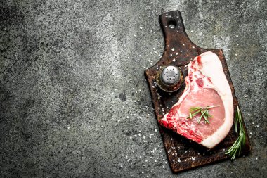 Çiğ domuz biftek otlar ve baharatlar ile. Rustik arka plan üzerinde.