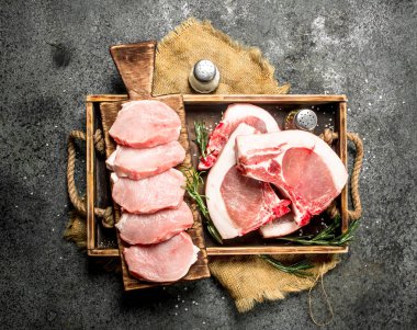 Otlar ve baharatlar içinde bir tepsi ile Çiğ domuz eti. Rustik arka plan üzerinde.