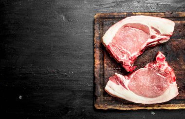 Bir kesme tahtası üzerinde çiğ domuz biftek. Siyah kara tahta.