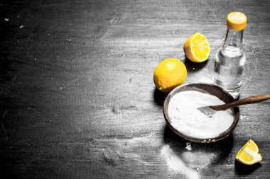 Baking soda in a bowl with vinegar and lemon slices. On the black chalkboard. clipart