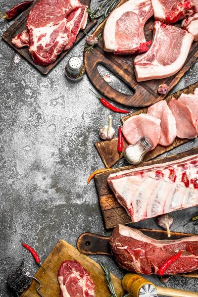 Farklı türde Çiğ domuz eti ve baharat ve otlar ile sığır eti. Rustik arka plan üzerinde.