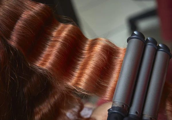 Red hair curled with triple barrel curling  iron Stock Image