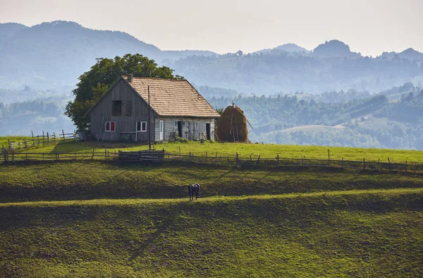 Venkovská krajina s dřevěnými stabilní v Rucar-otruby projít, Rumunsko — Stock fotografie