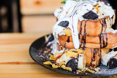 Çikolata sosu, tahıllar, kurabiye, beyaz krema, muz ve siyah yemek tatlı arka plan veya doku için vanilyalı dondurma hizmet ile tepesinde üçlü tost ekmeği.