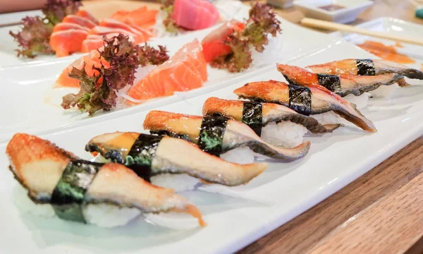 Anago (enguia) sushi com nori (algas) topo em arroz e nigiri (salmão) servir em prato branco, fundo de comida japonesa ou textura . — Fotografia de Stock
