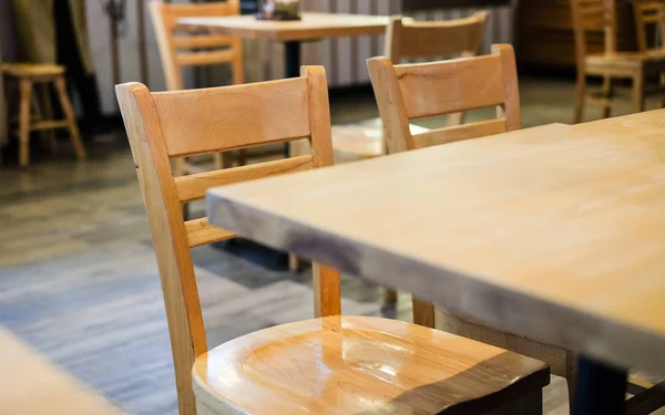 Molte sedie di legno marroni e tavolo impostato sul pavimento in legno alla caffetteria per sfondo o consistenza - concetto interno . — Foto Stock