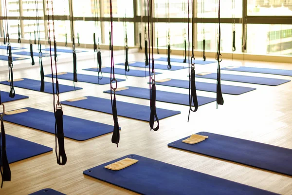 Many aerial yoga exercise equipment with blue cushions in gym for aerial silk (yoga fly) for background or texture - new trend of exercise concept.