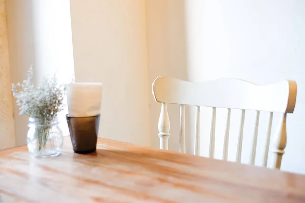 La bella pianta d'appartamento con vaso da fiori trasparente e tessuto in scatola nera incastonata su tavolo di legno marrone e sedia bianca, per cibo o sfondo o texture - concetto di interni . — Foto Stock