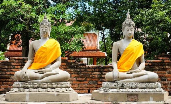 Magie des Sandstein-Buddha (die Haltung der Meditation) mit gelbem Gewand auf rechteckiger Plattform im "wat yai chaimongkol" (Provinz Ayutthaya - Thailand) - vintage & history concept. — Stockfoto