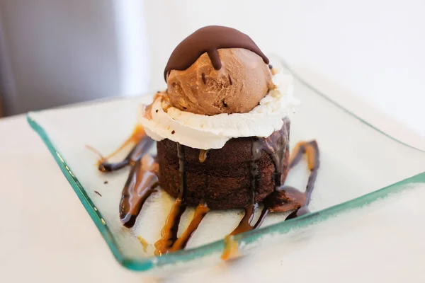 El pastel de lava de chocolate cubierto con crema batida, salsa y helado de "caramelo moca crumble" sirven en un plato claro para el fondo o textura del postre . — Foto de Stock