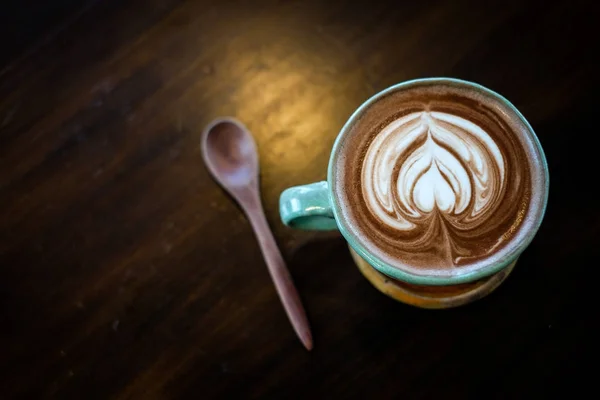 A cup of hot cocoa decorated with heart milk forth on the surface placed on a wooden tray and wooden spoon, for beverage/drink background or texture healthy diet concept. — Stock Photo, Image