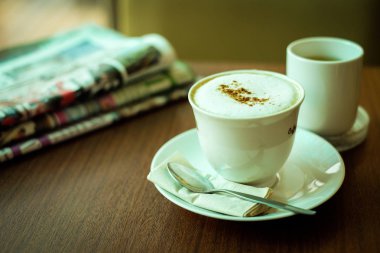 Toz kahve ve süt ileri yüzey hizmet çay, kaşık ve içecek arka plan - sağlıklı beslenme kavramı için doku ile plaka üzerinde gazete ve fincan sıcak kahve (kapuçino) süslenmiş.