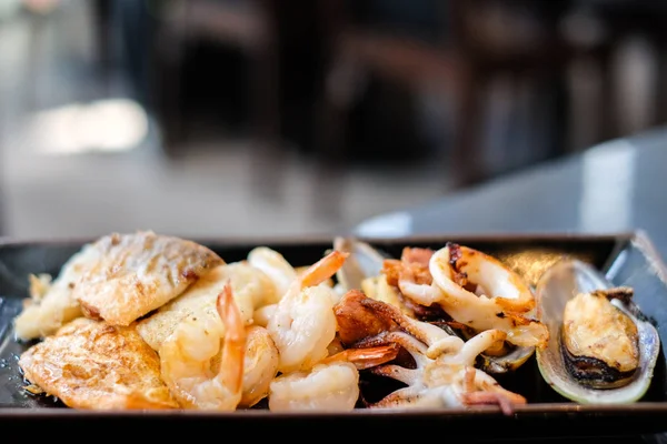 熱い食べ物の背景またはテクスチャ - 党シーフード概念の黒プレートで焼き食品 (エビ、イカやタコ、ニュージーランド ムール貝、サーモン、ドリー魚) として. — ストック写真
