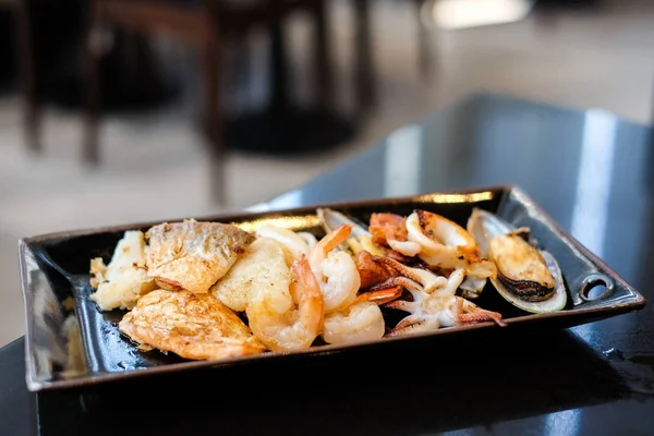 熱い食べ物の背景またはテクスチャ - 党シーフード概念の黒プレートで焼き食品 (エビ、イカやタコ、ニュージーランド ムール貝、サーモン、ドリー魚) として. — ストック写真