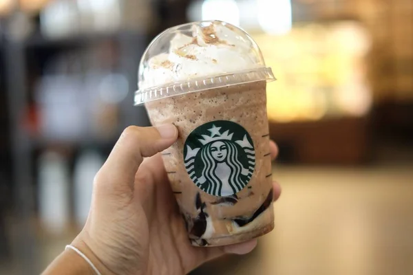 Bangkok, Tailandia - 30 de enero de 2018: Mano sosteniendo Frappuccino hielo (Cappuccino & Frappe) con fondo borroso y Starbucks signo de café . —  Fotos de Stock