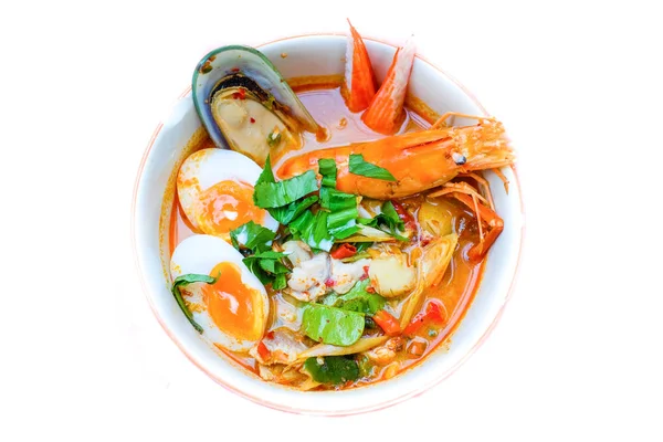 Thai noodle soup (Tom Yum Soup Recipe) with shrimp, dumpling fish, New Zealand mussels, crab and egg (onsen tamago) serve on white bowl for Thai food background or texture. — Stock Photo, Image