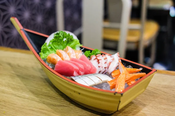 Conjunto de sashimi em tigela navio de madeira consistem em Toro, salmão (sake), polvo (tako), atum (maguro) e imitação caranguejo vara colocar no gelo - conceito de comida japonesa . — Fotografia de Stock