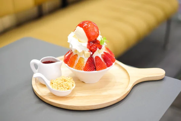 Strawberry kakigori (Japanese shaved ice dessert flavor with vanilla ice-cream) or bingsu (Korea dessert) serve on white bowl with strawberry sauce for sweet food background or texture.