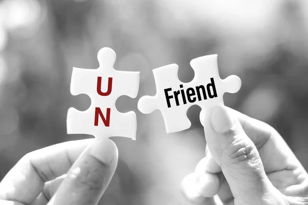 Unfriend (remove someone from a list of friends or contacts on a social networking website) word on white jigsaw is connect - idea match concept.