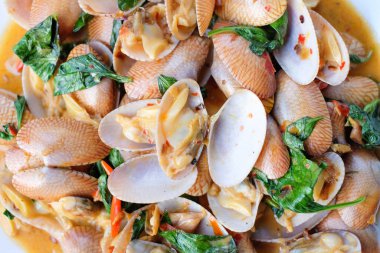 Yakın plan sıcak kavrulmuş midye, kavrulmuş biber ezmesi ve fesleğen kahverengi masada beyaz tabak setinde servis edilir. Ev yapımı yemek kavramı..