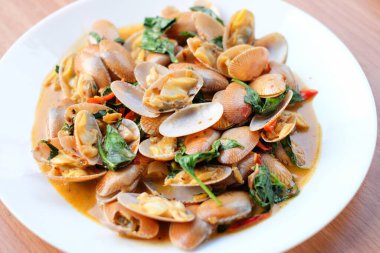 Kızarmış midye, kavrulmuş biber ezmesi ve fesleğen, kahverengi masada beyaz tabak seti üzerine servis edilir. Ev yapımı yemek konsepti..