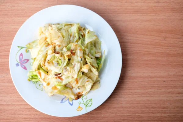 配鱼沙司的热炒卷心菜放在以褐色餐桌为主题的白菜上 自制食物概念 — 图库照片