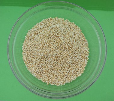 Quinoa (Chenopodium quinoa) bir cam kabın içinde yeşil arka plan üzerinde kabarık.