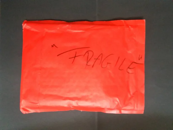 Fragile warning handwritten on a red mail parcel