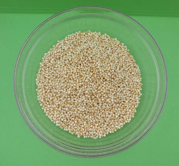 Quinoa (Chenopodium quinoa) bir cam kabın içinde yeşil arka plan üzerinde kabarık.