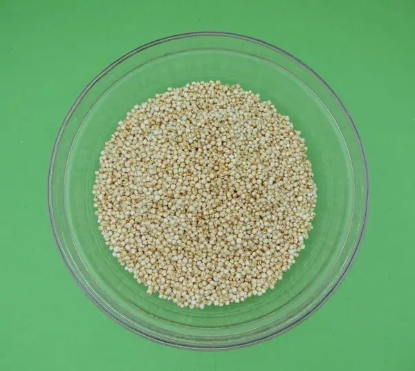 Quinoa (Chenopodium quinoa) bir cam kabın içinde yeşil arka plan üzerinde kabarık.
