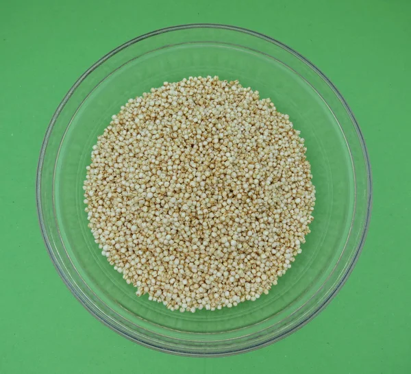 Quinoa (Chenopodium quinoa) bir cam kabın içinde yeşil arka plan üzerinde kabarık.
